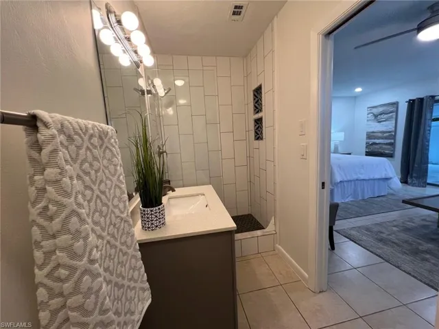 Bathroom featuring vanity, a tile shower, and tile patterned flooring