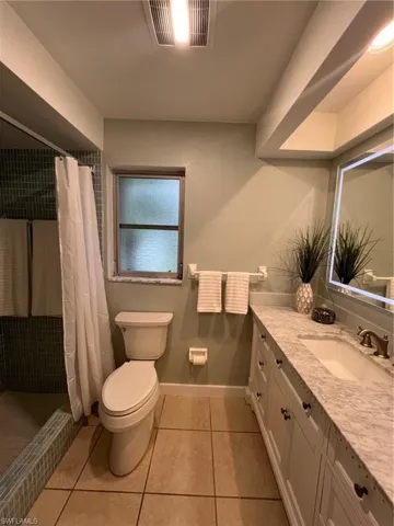 Bathroom featuring vanity, curtained shower, toilet, and tile patterned floors