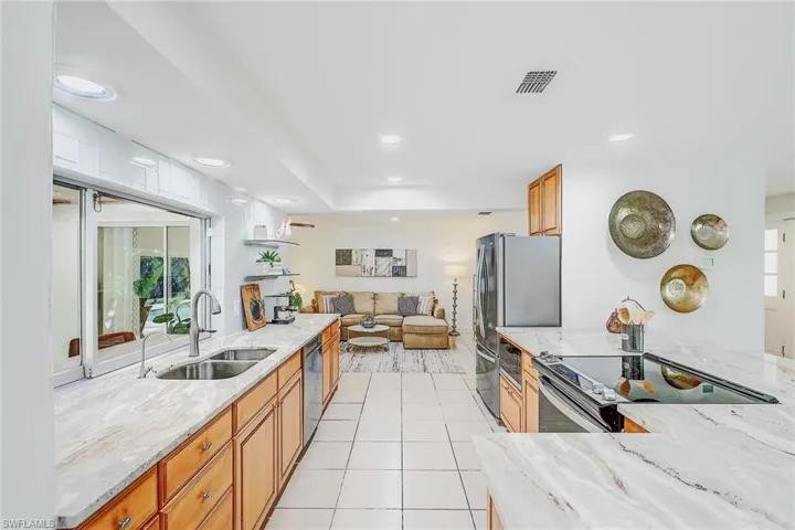 Kitchen with light stone counters, appliances with stainless steel finishes, light tile patterned floors, and sink