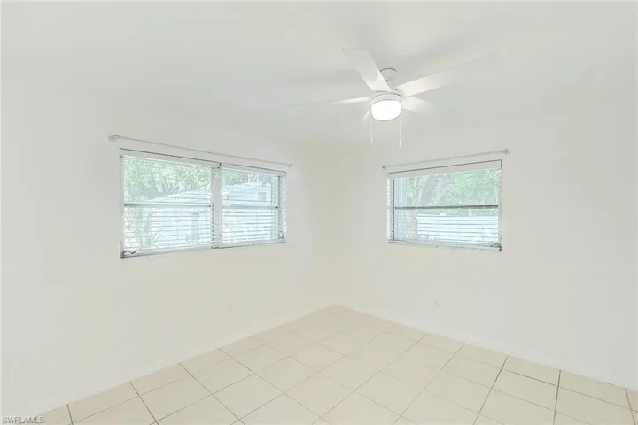 Tiled empty room featuring ceiling fan and plenty of natural light