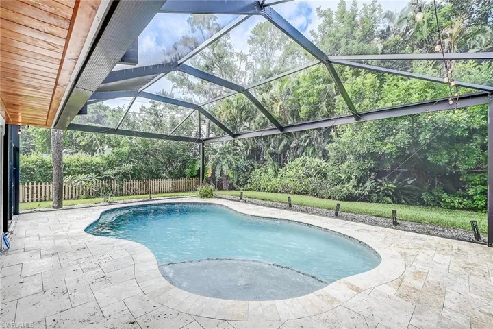 View of swimming pool featuring glass enclosure and a patio