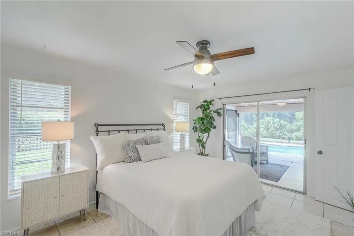 Tiled bedroom with access to outside, multiple windows, and ceiling fan
