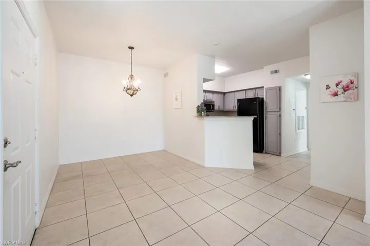 Kitchen featuring a notable chandelier, gray cabinets, black fridge, and light tile patterned floors