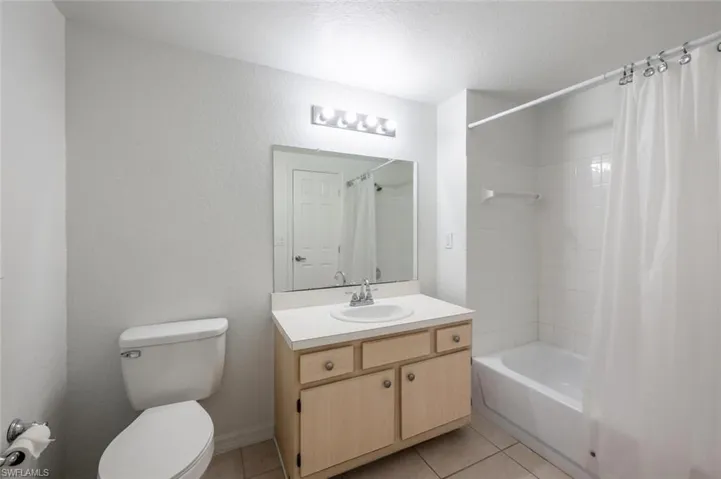 Full bathroom featuring tile patterned flooring, vanity, toilet, and shower / tub combo with curtain