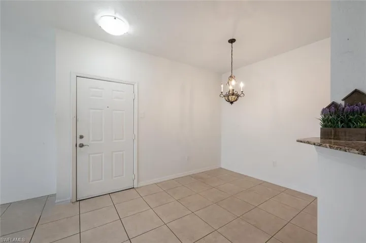 Unfurnished dining area with a chandelier and light tile patterned flooring