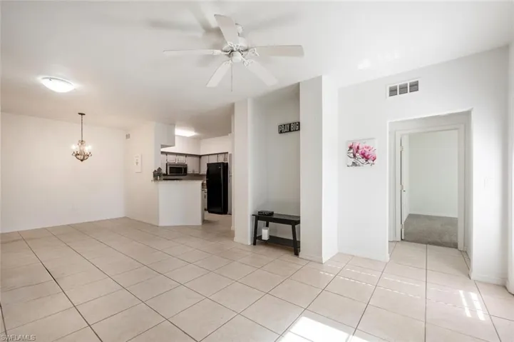 Unfurnished living room with ceiling fan with notable chandelier and light tile patterned floors