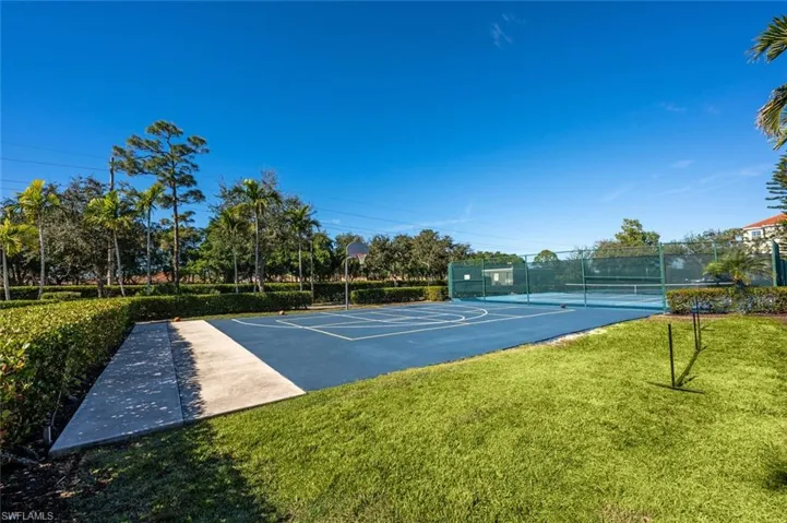 View of sport court featuring a lawn and tennis court