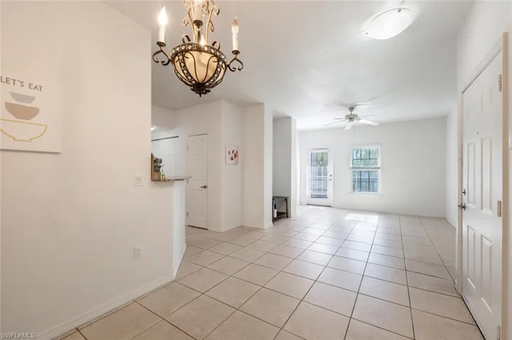 Spare room featuring light tile patterned floors and ceiling fan with notable chandelier