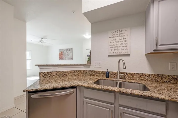 Kitchen featuring gray cabinetry, dishwasher, sink, ceiling fan, and stone countertops