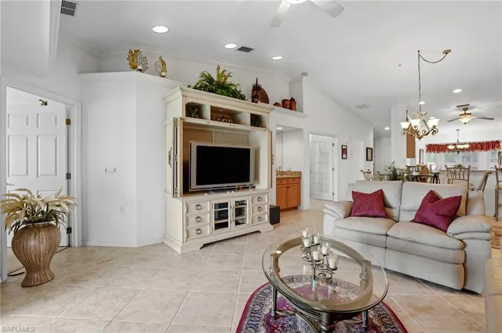 Living room featuring ceiling fan, crown molding, light tile patterned flooring, recessed lighting, and a chandelier