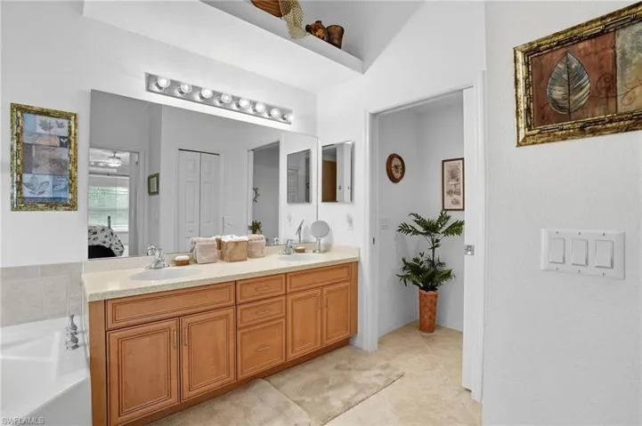 Bathroom featuring double vanity, a ceiling fan, light tile patterned floors, a garden tub, and a closet