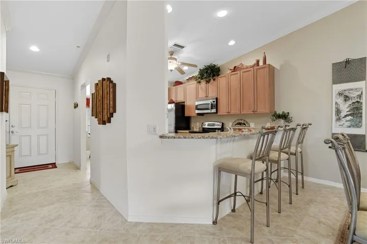 Kitchen featuring ornamental molding, appliances with stainless steel finishes, light stone countertops, a breakfast bar area, and recessed lighting