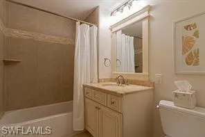 Built-in bathtub with subway tile surround, single vanity with integrated sink, framed mirror, and track lighting
