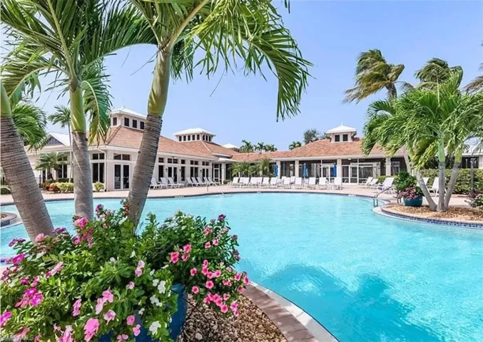 Resort-style pool with a curved edge, surrounded by mature palm trees and lush landscaping