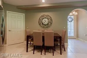 Recessed ceiling lighting illuminates the dining area with tile flooring and an arched doorway