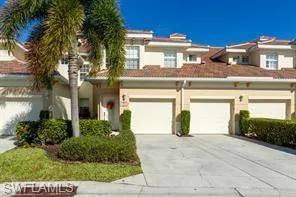 Mediterranean-style architecture with a tile roof, stucco exterior, multiple garage bays, and mature landscaping