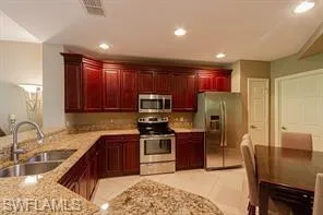 Kitchen featuring dark wood cabinetry, light-toned countertops, stainless steel appliances, and recessed lighting