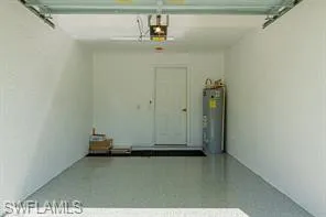 Attached garage with white-painted garage interior featuring a water heater, service door, and gray epoxy floor