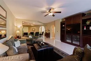 Recessed lighting, ceiling fan, built-in entertainment center, arched doorway, and tile flooring