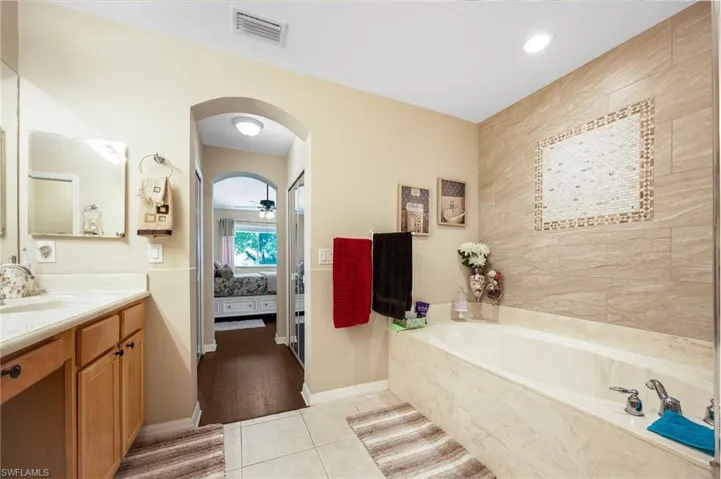 Ensuite bathroom with vanity, a garden tub, light tile patterned floors, ceiling fan, and recessed lighting