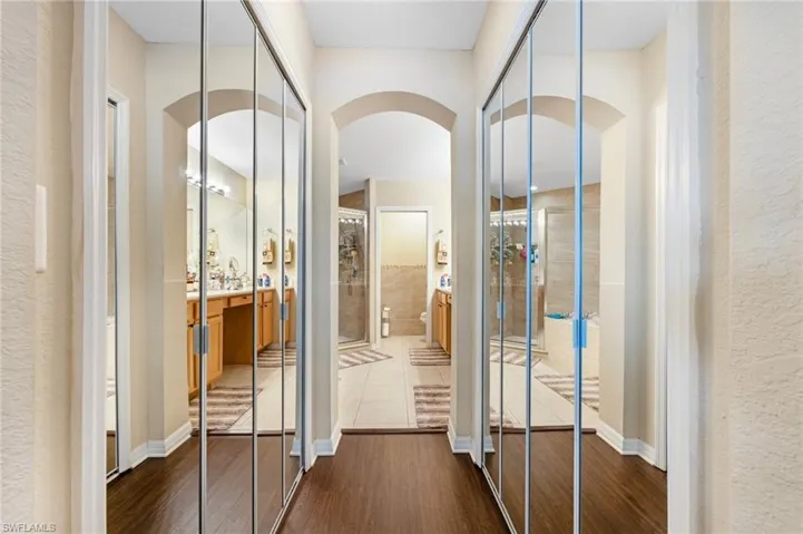 Hall with arched walkways, dark wood-style floors, and a textured wall