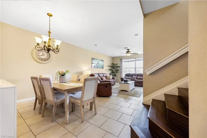 Dining room with stairway, light tile patterned floors, a chandelier, and a ceiling fan