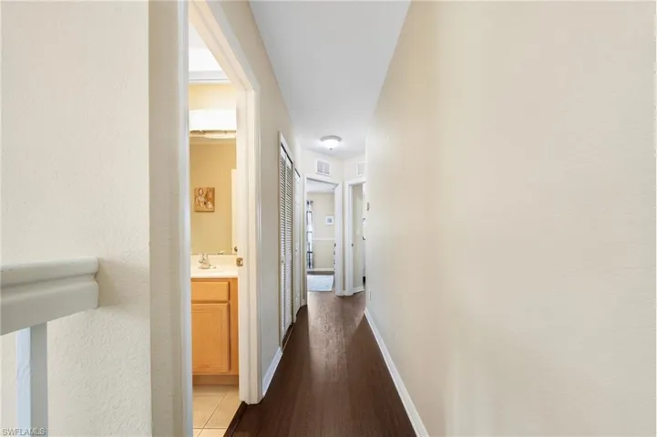 Corridor featuring dark wood-style floors and baseboards