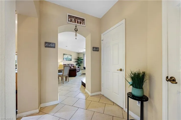 Hallway featuring arched walkways and light tile patterned floors