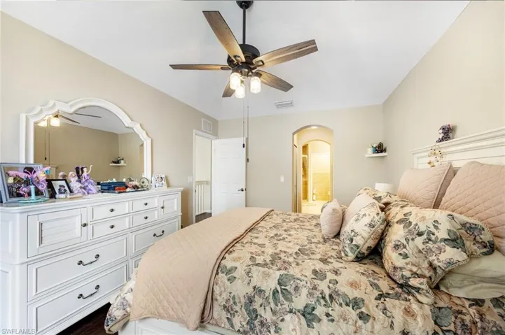 Bedroom featuring ensuite bath, ceiling fan, and arched walkways