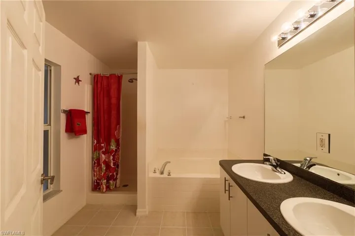 Bathroom with a garden tub, light tile patterned floors, a shower stall, and double vanity