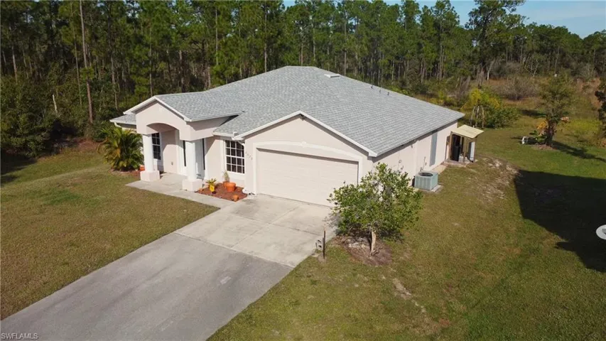 Ranch-style home featuring a front lawn, stucco siding, driveway, and roof with shingles