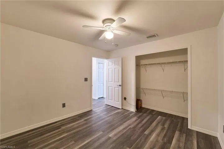 Unfurnished bedroom with dark wood finished floors, a closet, and a ceiling fan