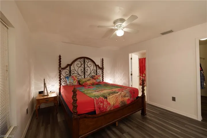 Bedroom with dark wood-style flooring, a ceiling fan, and a spacious closet