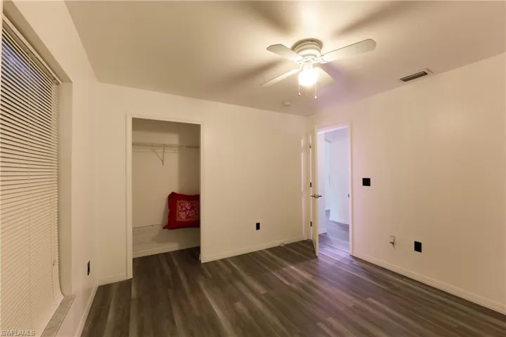 Unfurnished bedroom with dark wood-type flooring, a closet, and a ceiling fan
