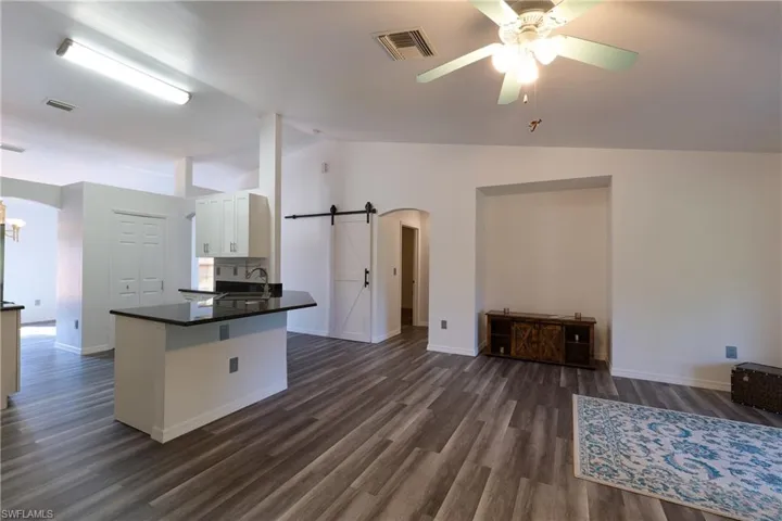 Kitchen featuring a barn door, lofted ceiling, a peninsula, arched walkways, and open floor plan
