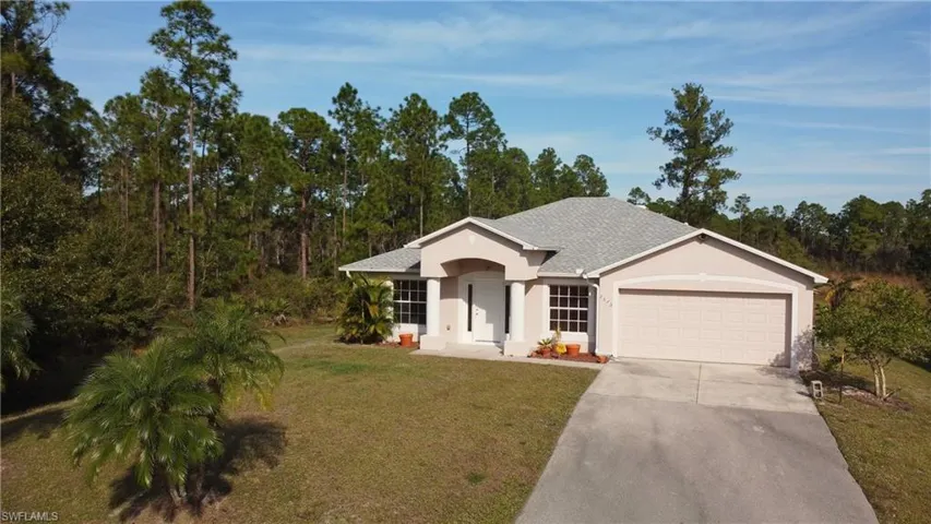 Single story home featuring concrete driveway, a front lawn, stucco siding, a shingled roof, and an attached garage