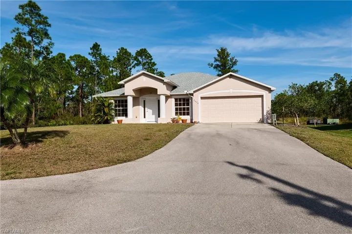 Ranch-style home with a front lawn, stucco siding, concrete driveway, and a garage
