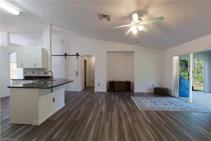 Kitchen with a barn door, arched walkways, lofted ceiling, a peninsula, and dark wood-type flooring