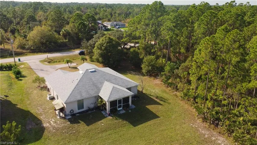 Aerial view of property and surrounding area featuring a forest