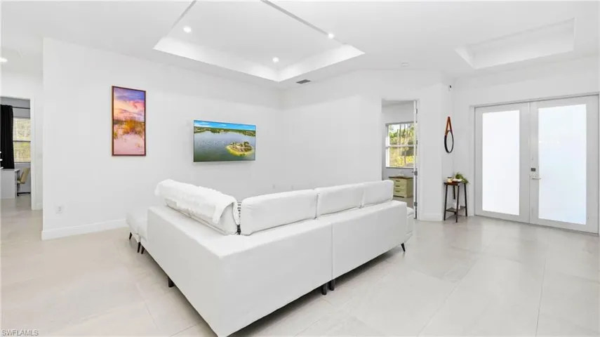 Living area with a tray ceiling, french doors, and recessed lighting