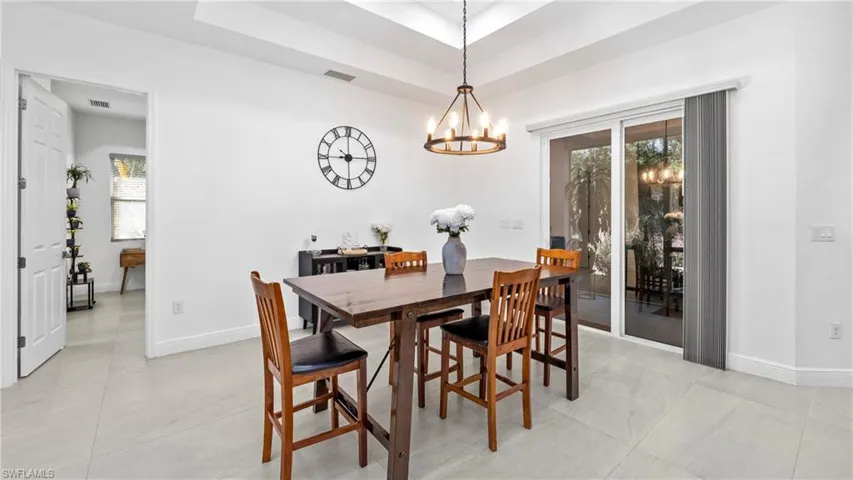 Dining area with a raised ceiling, hanging lights, and healthy amount of natural light