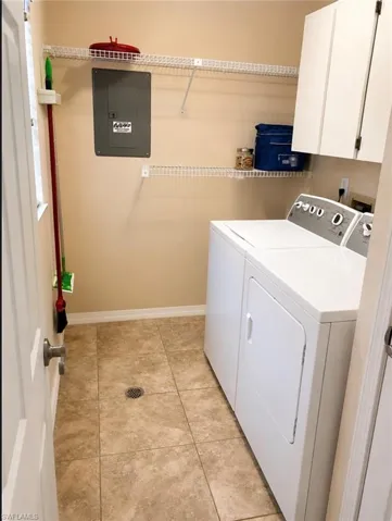 Dedicated utility area featuring a tiled floor with a central drain, upper cabinetry, and wire shelving