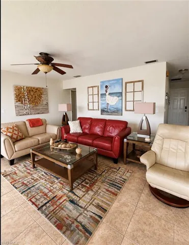 Open-concept living space featuring neutral tone tile flooring and a ceiling fan with integrated lighting
