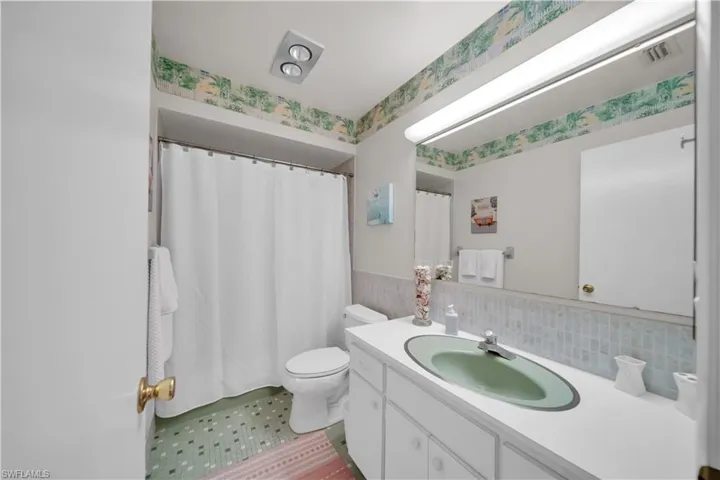 Bathroom featuring a vanity with a green oval sink, a large mirror, and patterned floor tiles