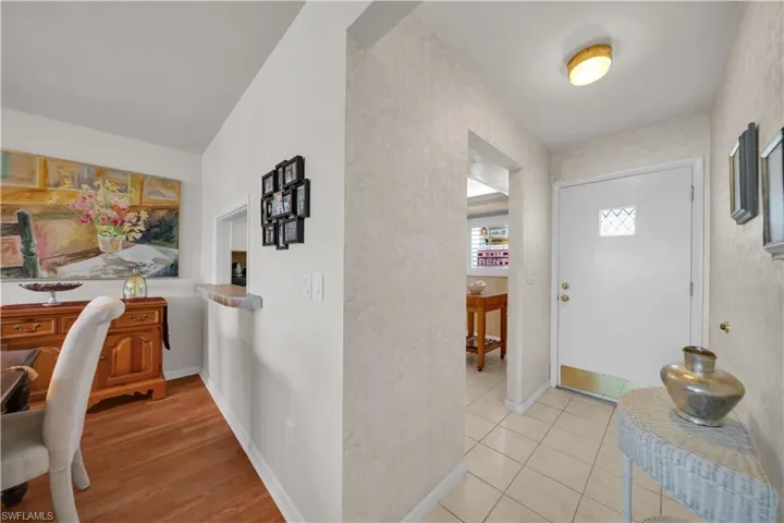 The entryway features a white front door with a decorative window, a ceiling light fixture, and tiled flooring