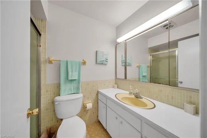 Bathroom featuring a white vanity with an integrated sink, a large mirror, and a shower with a sliding glass door