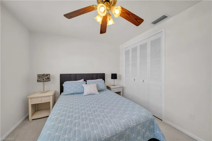 The room features white walls, a ceiling fan with light fixture, and white louvered closet doors