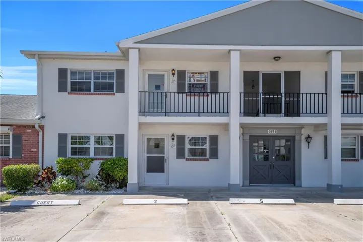 The property features a white stucco exterior with gray shutters and a gray roof