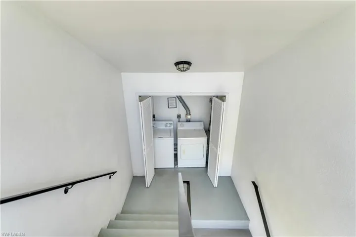 Dedicated laundry area with a washer and dryer, accessible via stairs with handrails