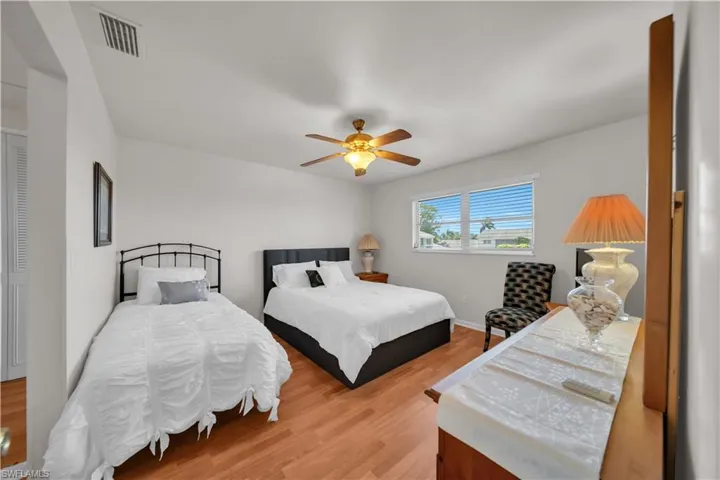 This room features wood-look flooring, a ceiling fan, and a window with horizontal blinds